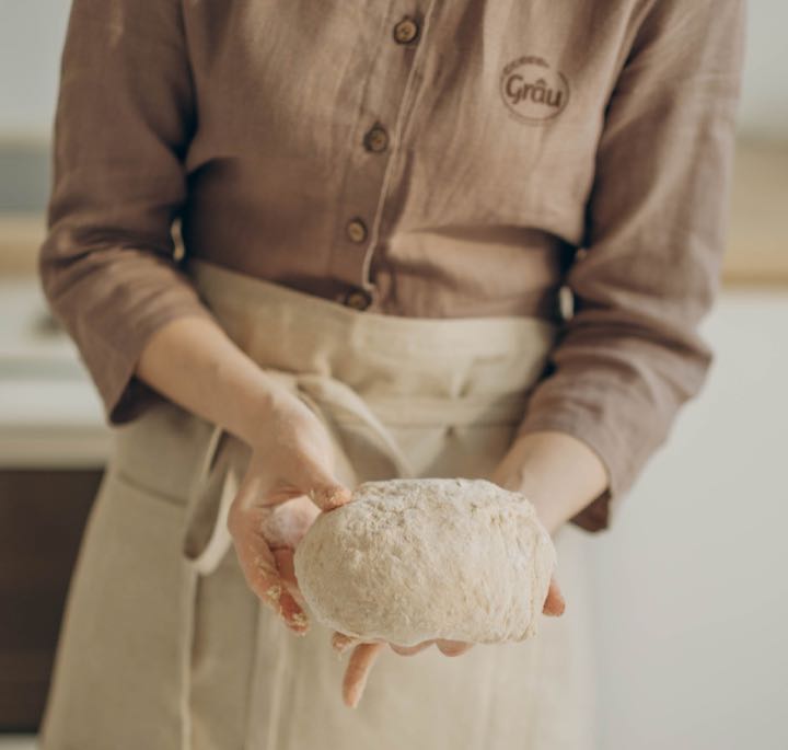 Padeira da Grâu segurando um pão de fermentação natural